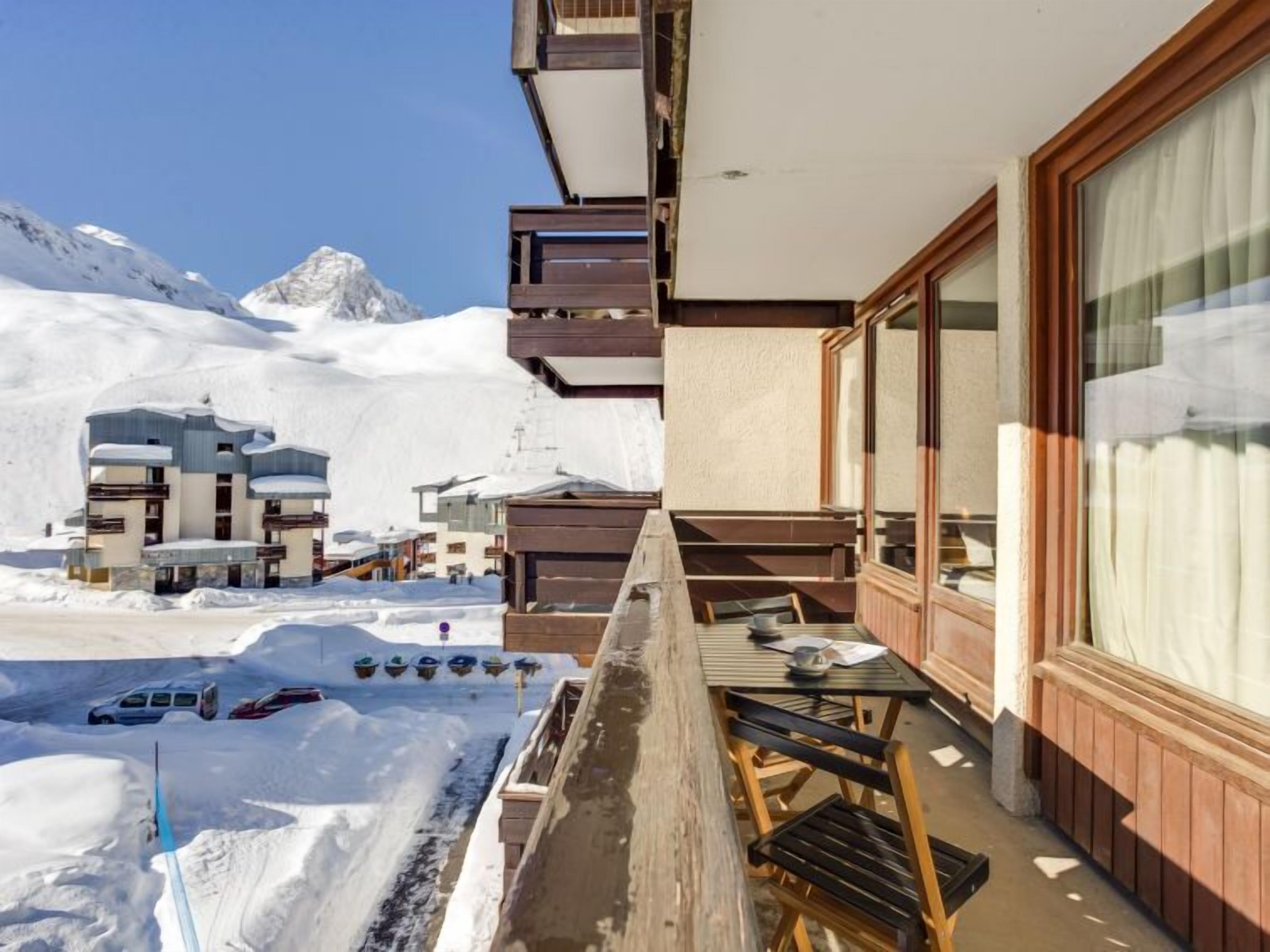 Ein mit Schnee bedeckter Berg mit einem modernen Gebäude, das Balkone und große Fenster hat.