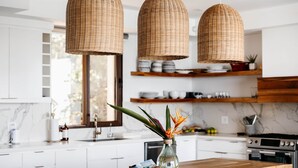 A kitchen with white cabinets, a wooden countertop, wicker pendant lights, and a vase with flowers. - Añoranza 3 BDRM: 2 Bedroom Villa + Casita 2 (Punta Blanca)