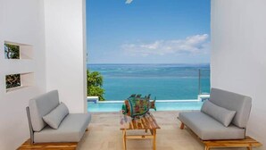 A room with two grey sofas, a wooden table, and a view of the ocean. - Añoranza 3 BDRM: 2 Bedroom Villa + Casita 2 (Punta Blanca)