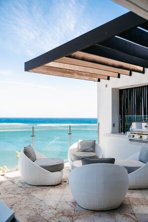 A modern outdoor seating area with a view of the ocean, a grill, and a covered patio. - Añoranza 3 BDRM: 2 Bedroom Villa + Casita 2 (Punta Blanca)