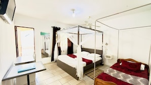 A bedroom with a four-poster bed, a desk, and a chair. - Hotel Appartement meublé Les Flots Bleu (Antananarivo)