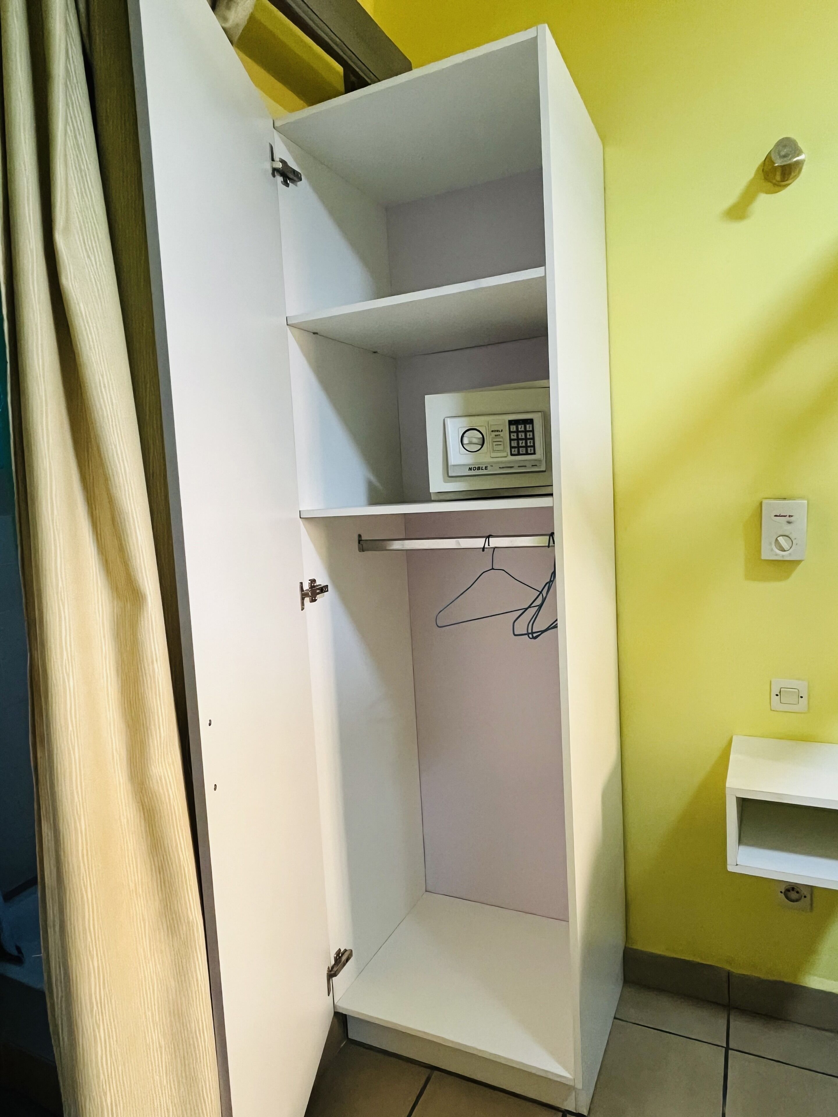 Une armoire blanche dotée d’une radio intégrée, d’une tringle pour suspendre les vêtements et d’une petite étagère.
