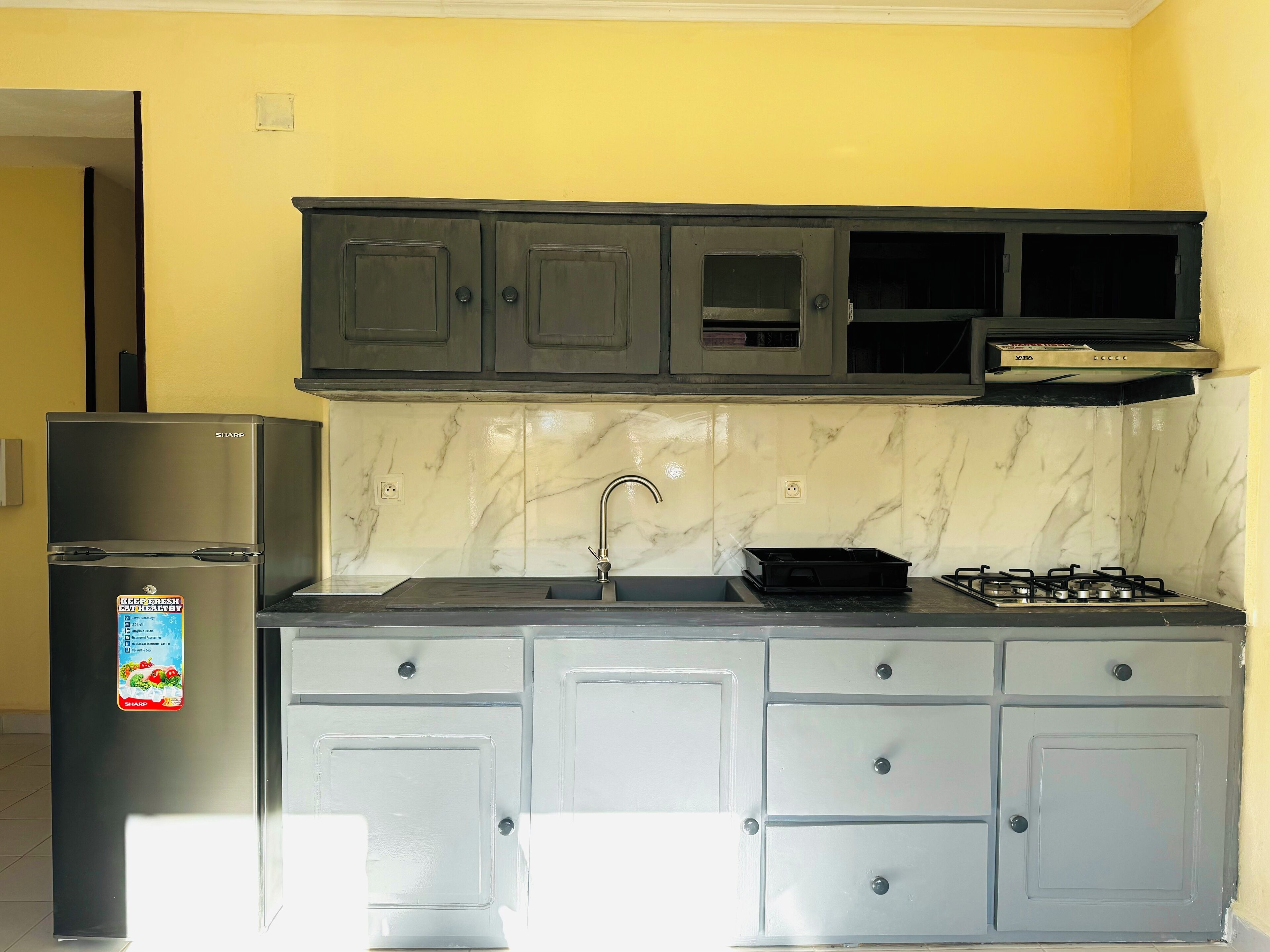 Una cocina con refrigerador, pileta, estufa y alacenas.