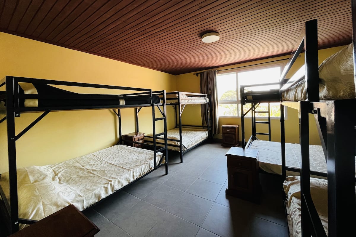 Un dormitorio con literas, una mesita de noche de madera y una ventana con cortinas.