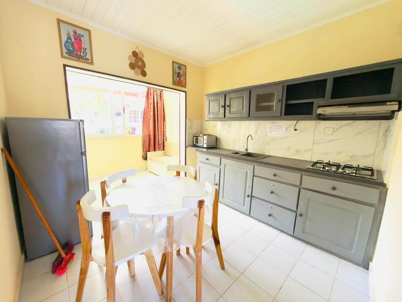 A compact kitchen with a dining table, grey cabinets, a microwave, and a gas stove.