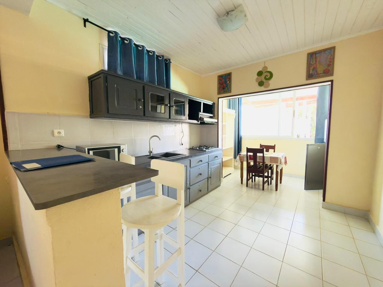 A kitchen with a bar counter, a dining table with chairs, and a refrigerator.
