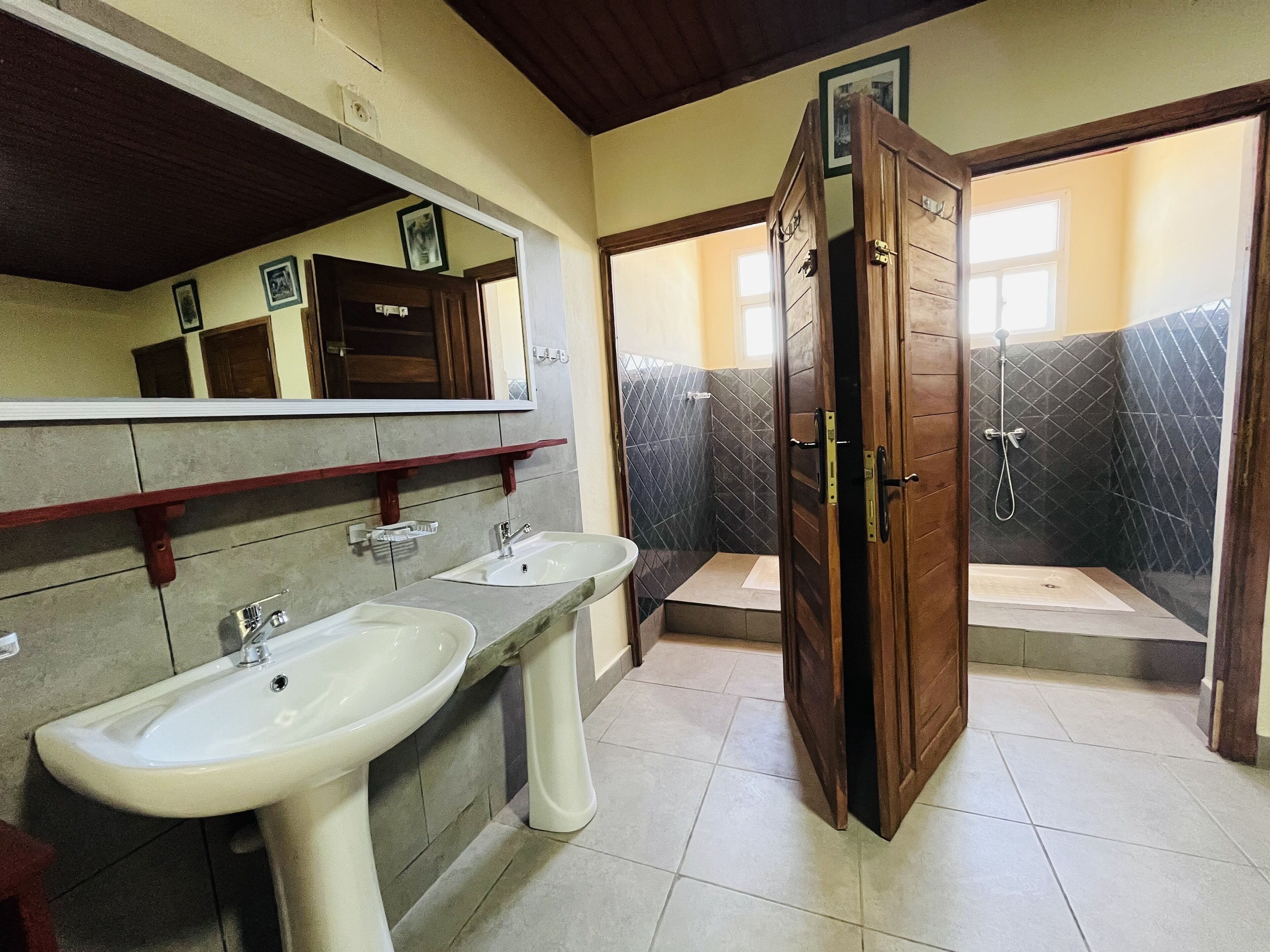 Une salle de bain avec deux lavabos, une douche et une porte en bois.
