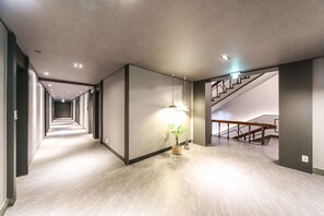 A modern hallway with a wooden staircase and a potted plant. - Gaya Mini Hotel (Gyeongju)