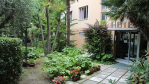 Pátio com plantas em vasos e entrada de um edifício.