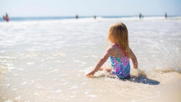 Uma criança brincando em águas rasas na praia.