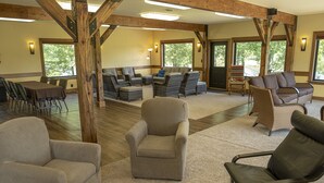 A spacious indoor area with multiple seating options, including sofas and chairs, arranged around a central table. - Great Views | Lakeside | Family-Friendly Barn | Reunions, Events, Retreats (Rolla)