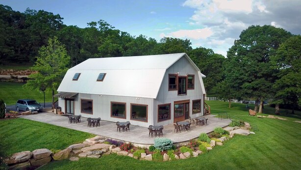 A two-story house with a large patio area, surrounded by a well-maintained lawn and stone edging. - Great Views | Lakeside | Family-Friendly Barn | Reunions, Events, Retreats (Rolla)