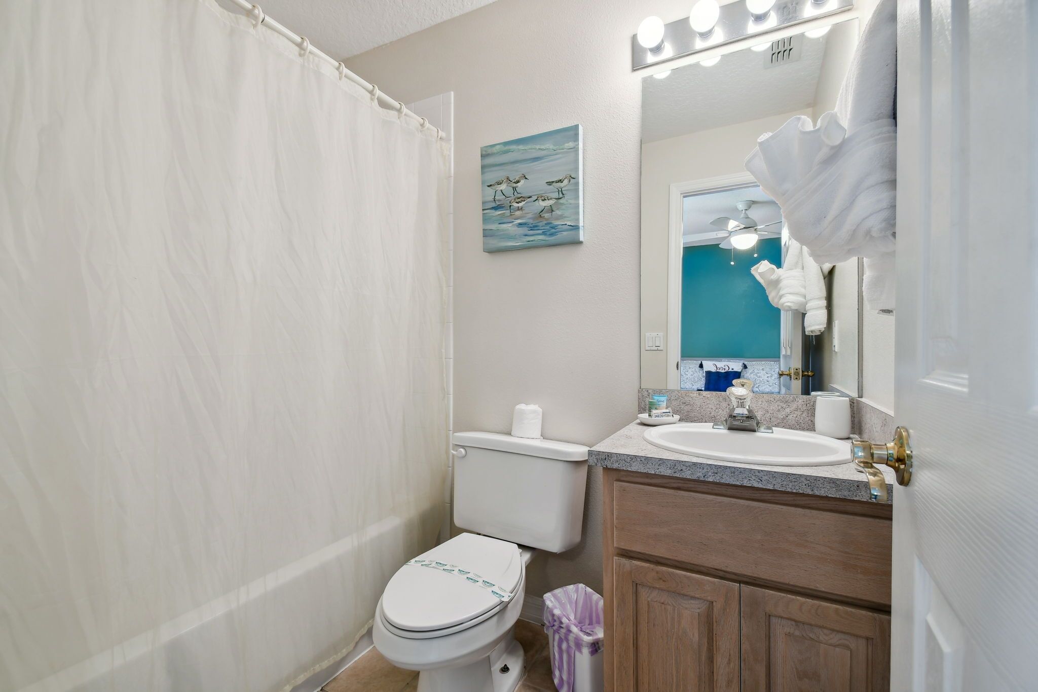 A bathroom with a toilet, sink, and mirror.