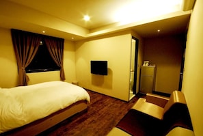 Una camera d'albergo con un letto, una televisione, una scrivania e un bagno.