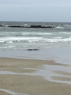 A beach with a rocky shoreline and waves crashing onto the sand.