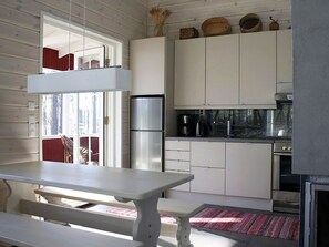 Een moderne keuken met witte kastjes, een roestvrijstalen koelkast en een eethoek met een bank.
