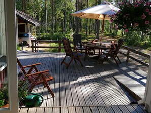 A wooden deck with outdoor furniture, a table, and chairs, surrounded by a forest. - Villa raita by Interhome (Rääkkylä)