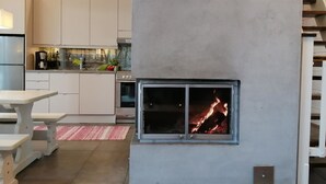 A modern kitchen with white cabinets, a built-in oven, and a fireplace with a glass door. - Villa raita by Interhome (Rääkkylä)