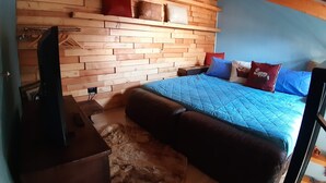 A bedroom with a wooden headboard, a bed with blue bedding, and a television on a wooden stand. - Ca 'De' Mumi, New Opening Old Town from 5 Apr '19 (Luino)