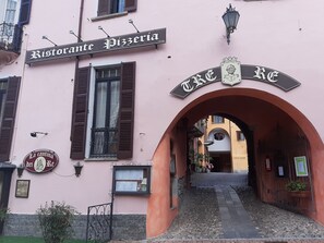 Um edifício com uma placa que diz "Ristorante Pizzeria" e um arco que dá acesso a outro edifício.