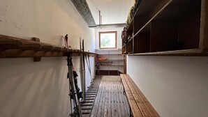 Ein schmaler Korridor mit Holzbänken und einem Skiständer.