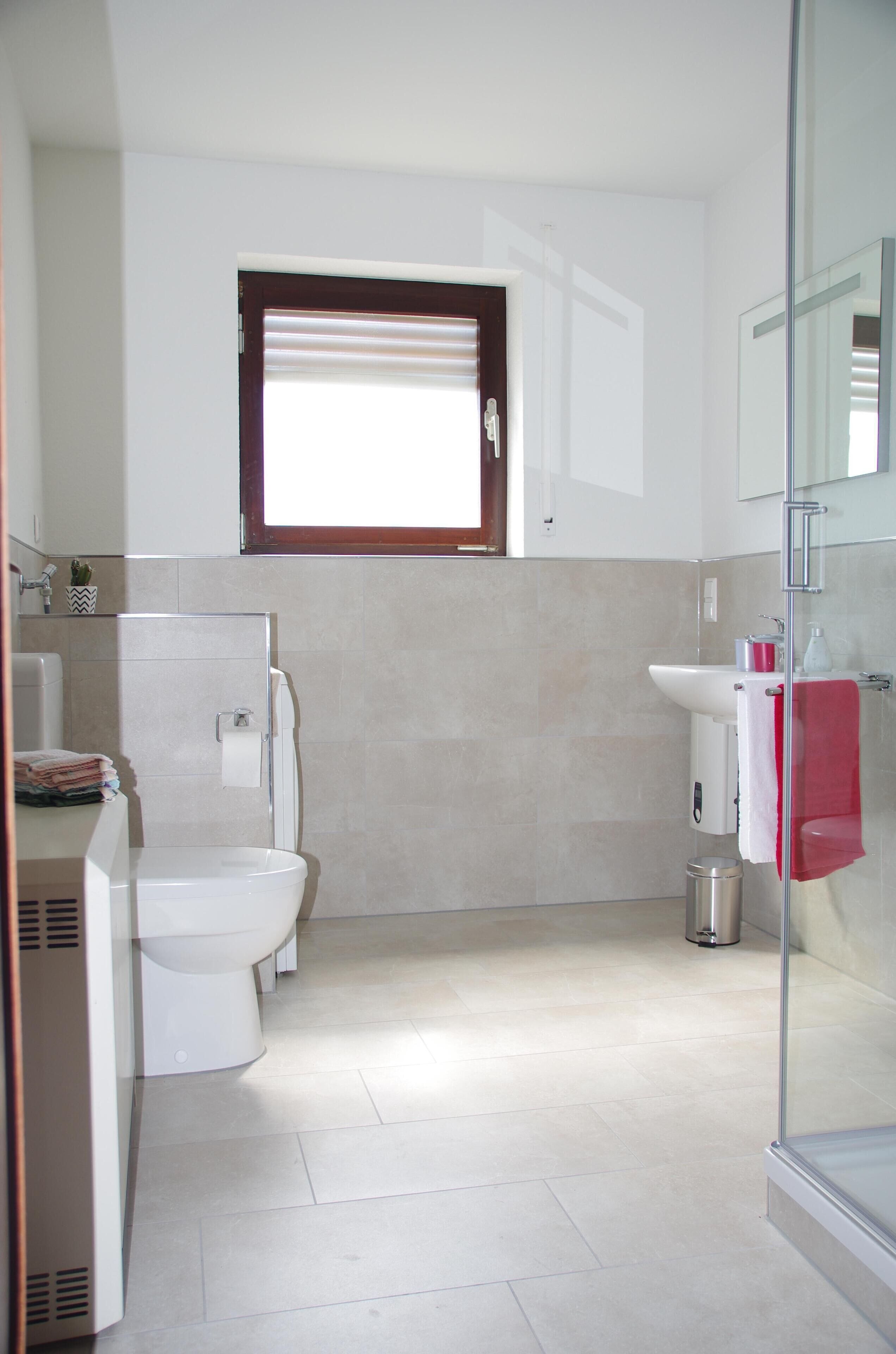 Un baño moderno con inodoro, lavabo y zona de ducha.
