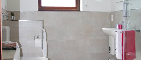 Un baño moderno con inodoro, lavabo y zona de ducha.