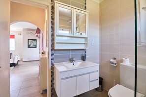Ein Badezimmer mit einem weißen Waschbecken, einem Spiegel und einer Toilette.