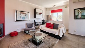 Ein modernes Wohnzimmer mit einem Glastisch, einer Couch und einem Essbereich mit roter Akzentwand.