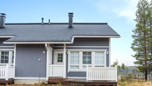 Een tweekapper met een grijze gevel, witte details en een overdekte veranda.
