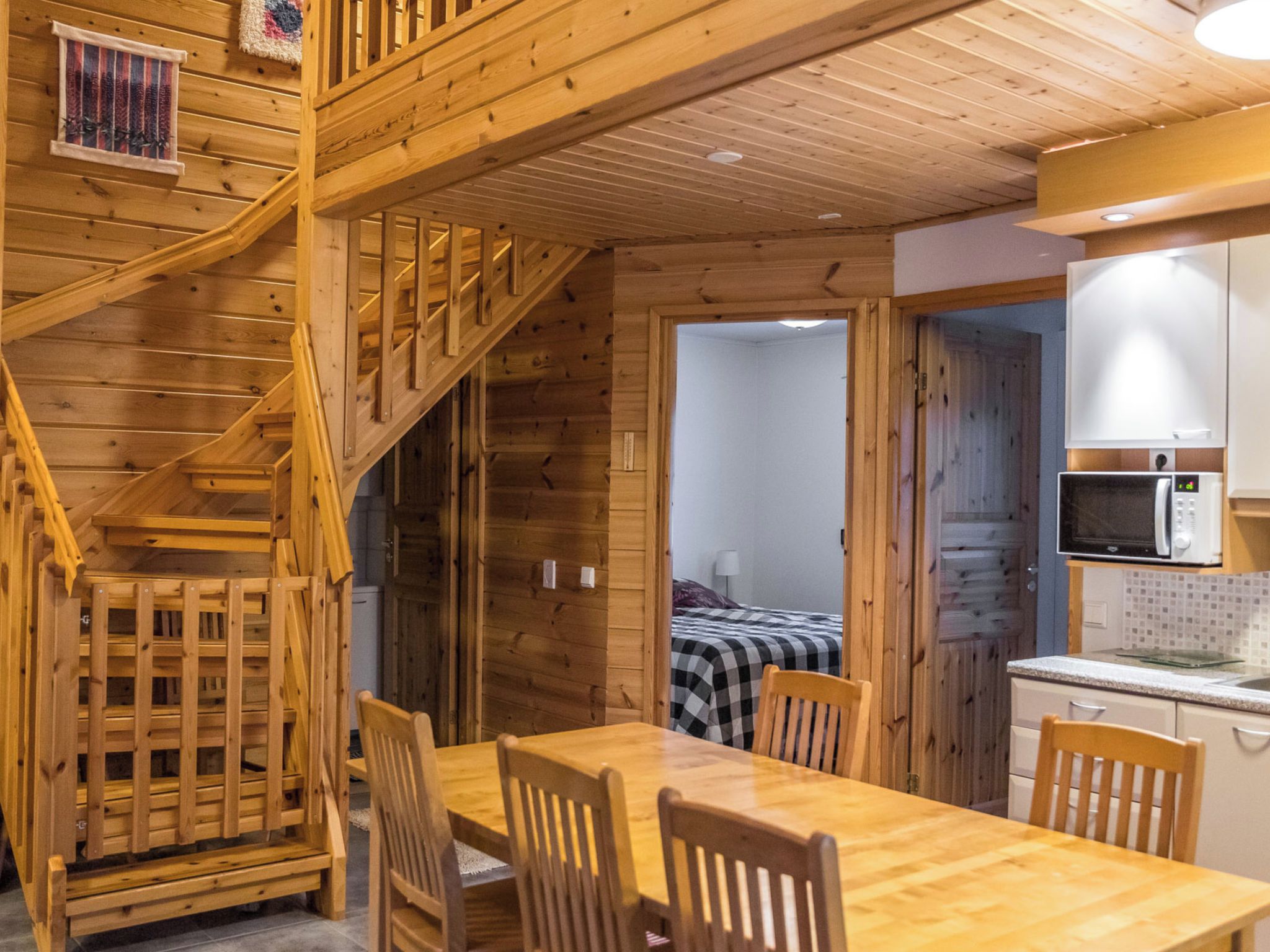 A wooden interior with a dining area, a staircase, and a kitchen.
