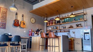 A modern bar area with wooden bar stools, a counter with a vintage radio, and a clock on the wall. - Time B&B (Hengchun)