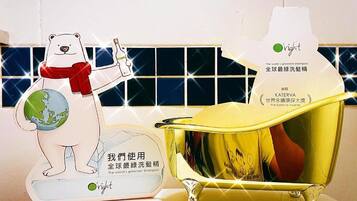 A polar bear holding a globe and a bottle of shampoo, with a golden bathtub and a mirror reflecting a person.