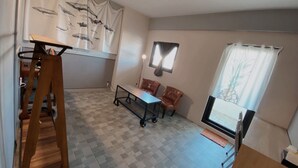 A room with a checkered floor, a table with chairs, a wooden ladder, and a large window with curtains. - Time B&B (Hengchun)