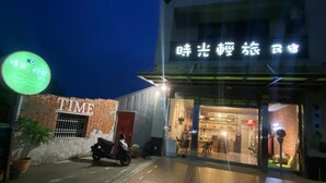 A building with a sign that reads "TIME" and another sign with Chinese characters. There is a motorcycle parked outside. - Time B&B (Hengchun)