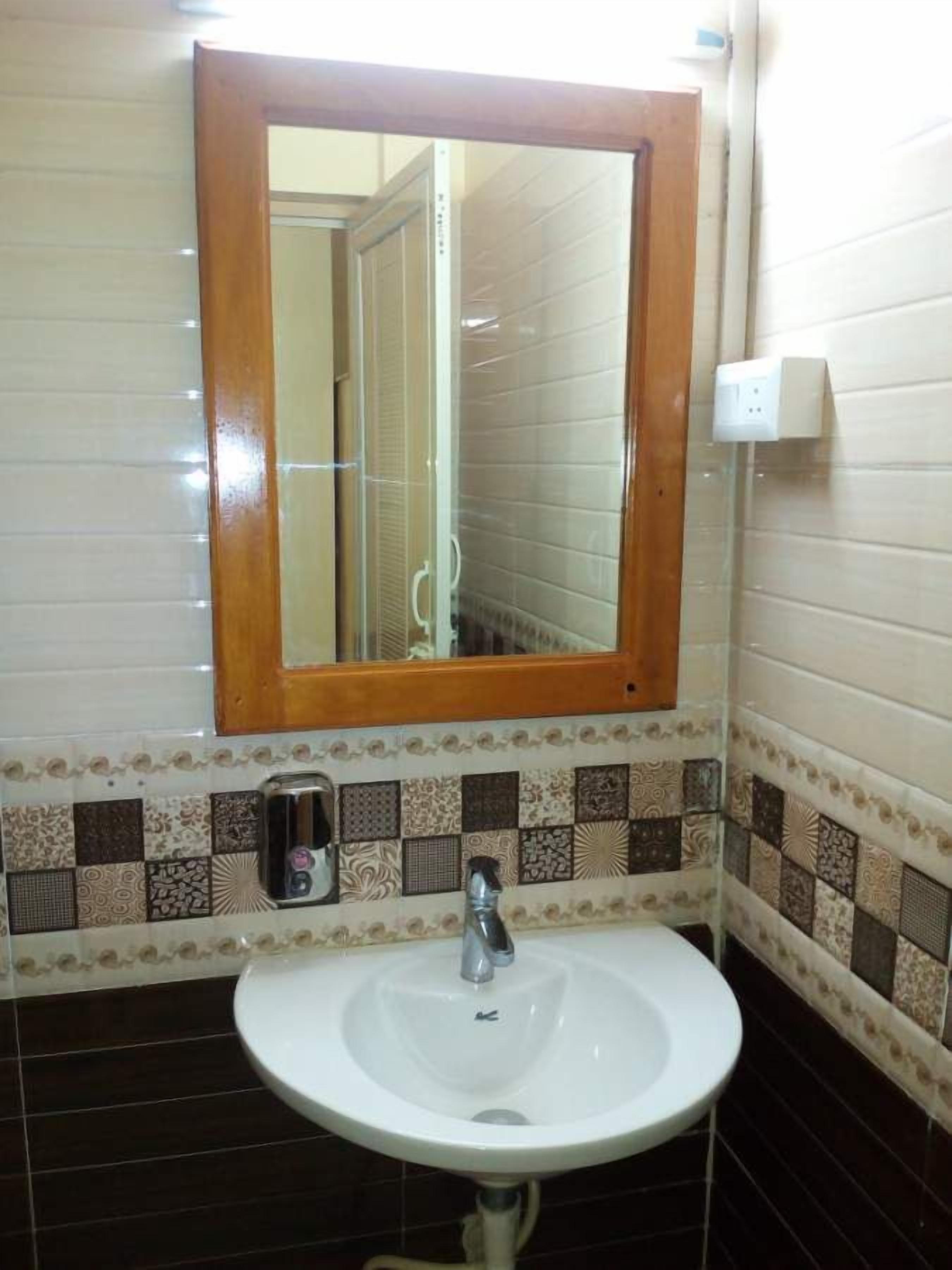 A bathroom with a white sink, a wooden-framed mirror, and patterned tiles.