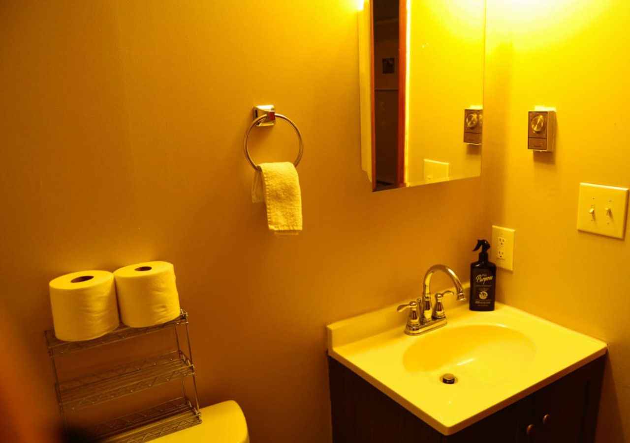 Un baño con lavamanos, inodoro y dos rollos de papel higiénico en un dispensador.