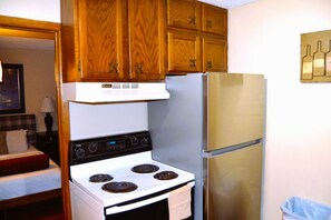 A compact kitchen with wooden cabinets, a white stove, and a stainless steel refrigerator.