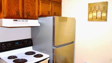 Une cuisine avec des meubles en bois, un réfrigérateur en acier inoxydable et une cuisinière blanche.