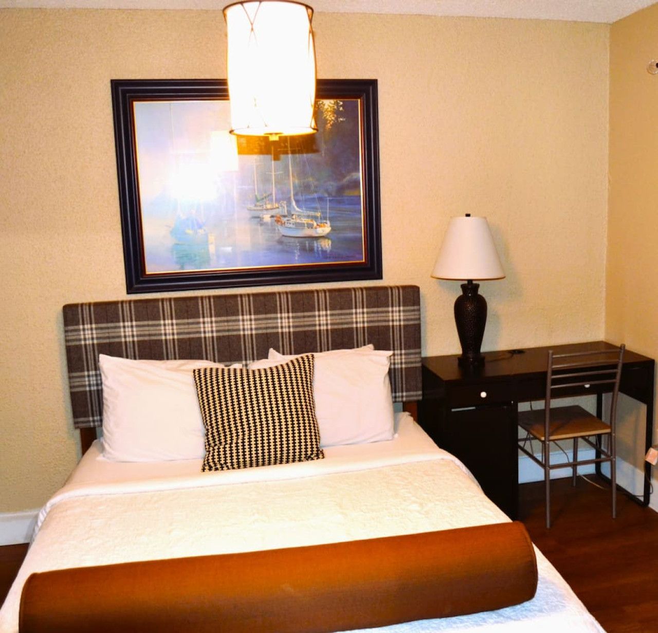 Une chambre d’hôtel avec un lit, un bureau et une chaise.