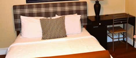 A hotel room with a bed, a desk, and a chair.