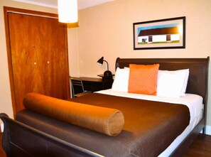 Una habitación de hotel con cama, escritorio y silla.