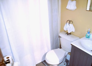 Un baño pequeño con inodoro, lavamanos y cortina de ducha.