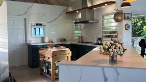 Een moderne keuken met een marmeren aanrechtblad, een inbouwoven en hanglampen.