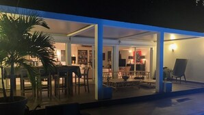Een terras buiten met een zwembad, zitplaatsen en een eethoek.