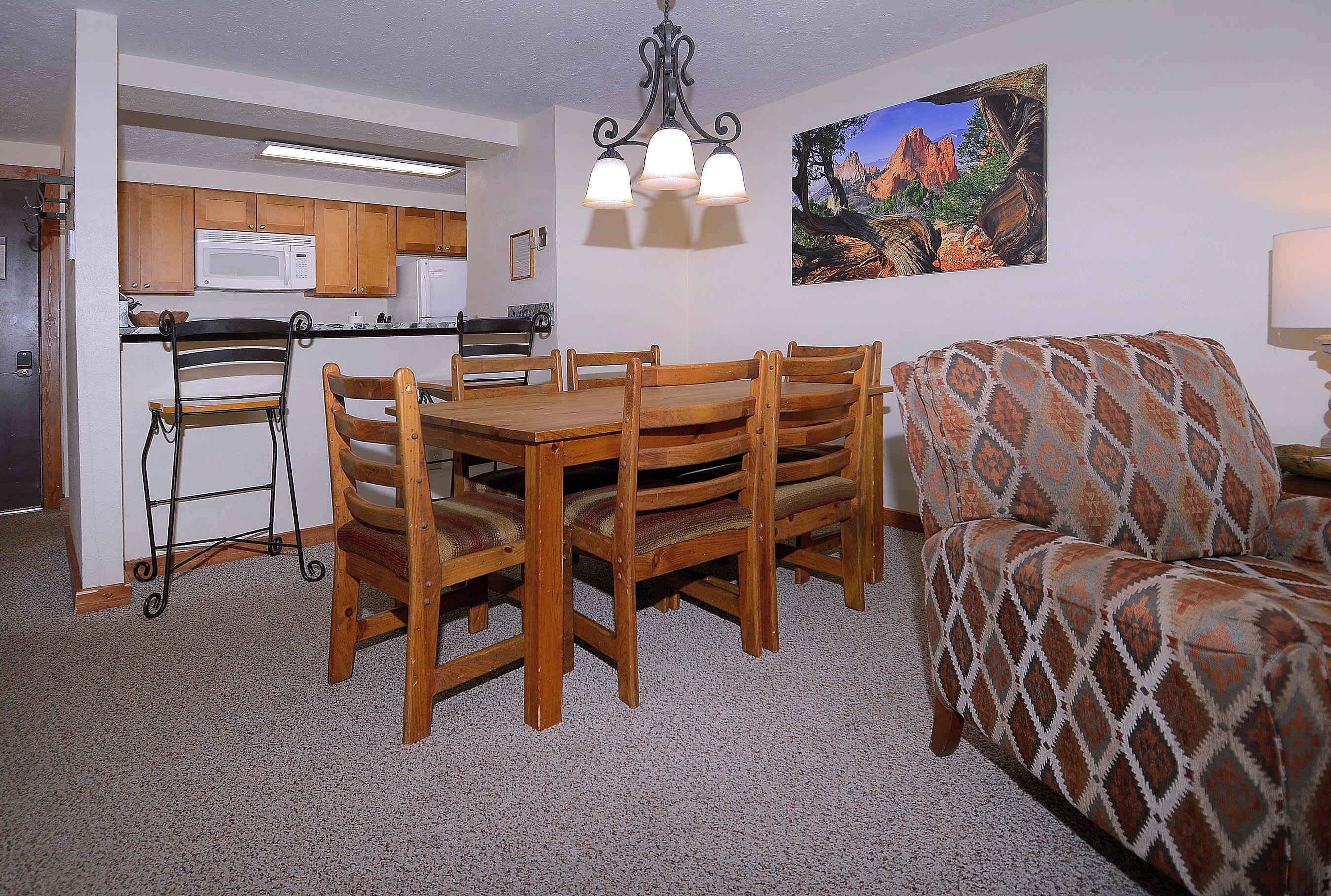 Un comedor con una mesa y sillas de madera, un microondas y un cuadro en la pared.