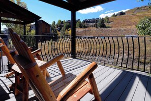 A wooden deck with a railing, overlooking a hilly landscape with buildings. - Silvery Lupine, Hot tub, pool, shuttle (Crested Butte)
