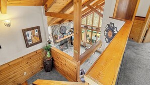 A wooden interior with a sloped ceiling, stone wall, and a fireplace. - Summer Retreat - Treetop View Cabin with Hot tub & Pool Table (Gatlinburg)