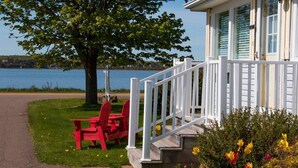 A lakeside cabin with a white porch, red Adirondack chairs, and a view of the lake. - Waterfront Vacation Home-4 bedrooms-2.5bath-Laundry room inside-2 heat pumps (York)