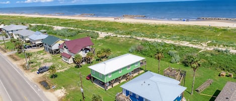 Aerial view of Camp PJ's a beachfront vacation rental in Grand Isle, LA showing the home's coastal setting near the sandy beach and Gulf waters.